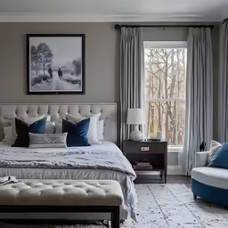 a bedroom with gray walls, a bed, and two chairs