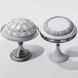 two silver pedestals with floral designs on them
