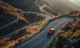 the red car is driving down the winding road