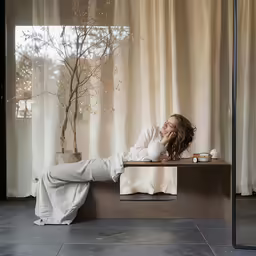 woman resting on bench next to window in building
