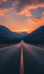 the empty highway in front of a mountain range with a beautiful sky