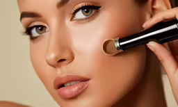 a woman putting a small, shiny foundation on her face