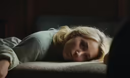 a woman laying on top of a brown couch
