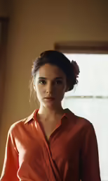 a woman wearing an orange shirt and a flower in her hair