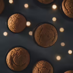 overhead view of baked muffins in black cups with white lights