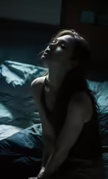a woman in a black shirt is sitting on a bed