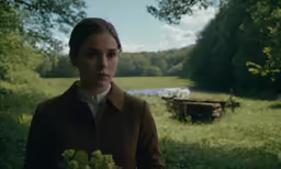 a woman in a brown coat with a brown and white collared shirt