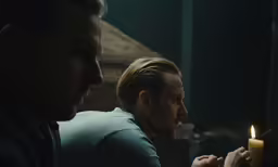 two people with a candle are looking at the other men