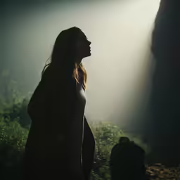 a woman standing in the dark looking up