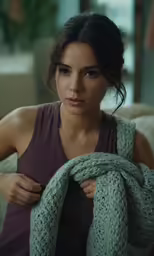a woman in tank top holding sweater over shoulder