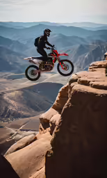 a man on a dirt bike jumping off the side of a mountain