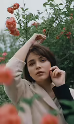 a young woman is sitting in front of a bush with orange flowers