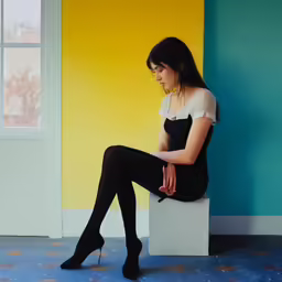 woman wearing black stockings and a white top sitting on a box