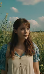 girl in a field with blue skies and clouds