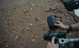someone using a camera to record an unreached rocky hill