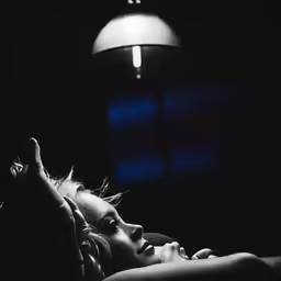 a woman laying down in the dark near a light