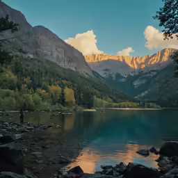 a man is standing on the shore near the mountains