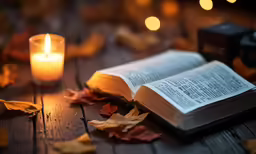 an open bible next to some burning candles