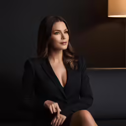 a beautiful woman in black sitting on top of a couch