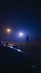 two people standing by cars on a road at night