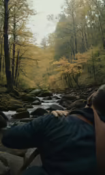 a man sitting on a wooden deck over looking a creek