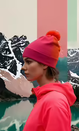 a girl in a red hoodie standing by a lake wearing a bright pink coat and a matching beanie
