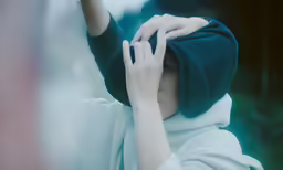 a person covering their eyes and holding a green object