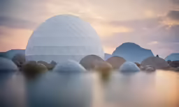 the ice ball is sitting on a lake near many small rocks