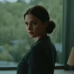 a beautiful woman wearing a black jacket standing in front of a window