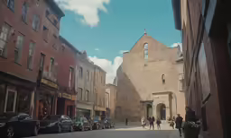 the people are walking down the narrow street in the city