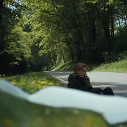 there is a woman sitting on the side of the road talking on her phone