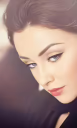 a close up of a woman with a black dress and bright blue eyes