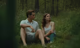 a woman and man sitting in the woods