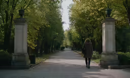 a woman is walking down a path with trees
