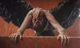 woman looking down and hiding her head behind a rail