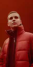 a young boy in red jacket posing with his hand up