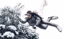a woman in silver outfit flying through the air