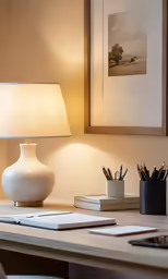 a white vase on a desk in front of a picture
