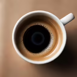 a cup of coffee is placed on a brown table