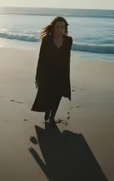 a woman walking on the beach at sunset