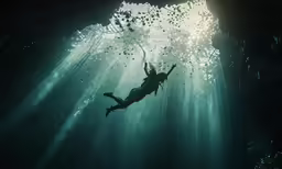 a man diving underwater in an underwater cave