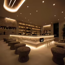 a large bar with brown stools sits in the middle of a large hall