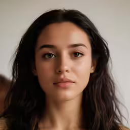 a woman with dark hair wearing an open collar
