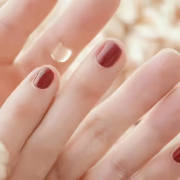 two hands with maroon and gold nails are in the center