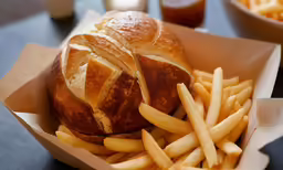 an open loaf of bread with fries sits on a table