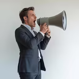 a man in a suit is shouting into a megaphone