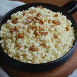 a pan of rice and nuts with a wooden spoon