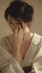 a woman in white sits and looks down