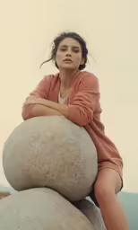 a woman sits on a rock posing for a picture