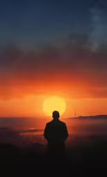 the man is standing and watching the sunset